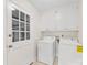 Bright laundry room with washer, dryer, white cabinets, and a door leading to the garage at 5817 Portburn Rd, Charlotte, NC 28211