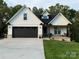 Charming home featuring a black garage door, front porch swing, and manicured lawn at 602 Kames Nw Ct, Conover, NC 28613