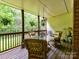 Serene covered deck with wicker furniture, a glass table, and views of the surrounding greenery offers a relaxing outdoor space at 6645 Gaywind Dr, Charlotte, NC 28226