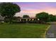 Charming ranch-style home with a well-manicured lawn and mature trees under a colorful sunset at 6813 Rebel Rd, Marshville, NC 28103