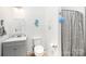 The white and gray bathroom has an updated vanity and features a shower with a gray and white patterned curtain at 8300 Loma Linda Ln, Waxhaw, NC 28173