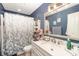 A traditional bathroom with a floral shower curtain, white vanity, and a blue accent wall create a relaxing atmosphere at 8300 Loma Linda Ln, Waxhaw, NC 28173