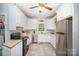 Well-lit kitchen with white cabinets, stainless steel appliances, tile flooring and a view to the laundry at 8300 Loma Linda Ln, Waxhaw, NC 28173