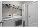 Well-lit laundry room featuring modern washer, dryer, storage, and convenient overhead shelving at 1548 Striped Bass Ln, Clover, SC 29710