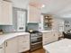 Modern kitchen with white cabinets, quartz countertops, subway tile backsplash, stainless steel oven, and wooden floating shelves at 335 Greystone Rd, Charlotte, NC 28209