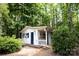 Charming white outbuilding with blue trim nestled in a lush, wooded setting at 432 Partridge Pl, York, SC 29745