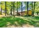 Spacious backyard with mature trees, green grass, and a rear view of a brick home with a deck at 6447 E Nc 27 Hwy, Iron Station, NC 28080