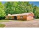 Spacious single-story brick house with a long driveway and well-maintained lawn with beautiful green trees at 6447 E Nc 27 Hwy, Iron Station, NC 28080