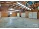 Spacious three-car garage with wooden beams, concrete floors, and three white garage doors at 6447 E Nc 27 Hwy, Iron Station, NC 28080