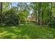 Large, grassy backyard with mature trees providing shade, offering a serene outdoor space at 6824 N Baltusrol Ln, Charlotte, NC 28210