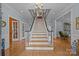 Grand foyer with a staircase, light wood floors, and an elegant chandelier creates a welcoming entrance at 6824 N Baltusrol Ln, Charlotte, NC 28210