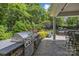 Outdoor kitchen area with a built-in grill, counter space, and seating overlooking the landscaped backyard at 6824 N Baltusrol Ln, Charlotte, NC 28210