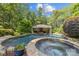 Beautiful in-ground pool with a covered lounge area and stone accents surrounded by lush landscaping at 6824 N Baltusrol Ln, Charlotte, NC 28210
