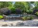 Stunning pool area with a stone waterfall feature and meticulously manicured landscaping at 6824 N Baltusrol Ln, Charlotte, NC 28210
