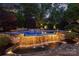 Outdoor pool featuring a rock waterfall, ambient lighting and lush landscaping, perfect for relaxation at 6824 N Baltusrol Ln, Charlotte, NC 28210