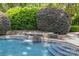 Close-up of the in-ground pool with a stone waterfall and beautifully landscaped surroundings at 6824 N Baltusrol Ln, Charlotte, NC 28210