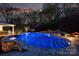 Beautifully lit outdoor pool and jacuzzi at night, surrounded by lush landscaping at 6824 N Baltusrol Ln, Charlotte, NC 28210