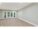 Open living room with light wood floors, neutral paint, and glass doors to the backyard at 7004 Quail Hill Rd, Charlotte, NC 28210