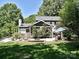 Backyard featuring a stone patio, seating area, a lush lawn, and mature trees providing shade and privacy at 8200 Lansford Rd, Charlotte, NC 28277