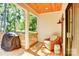 Inviting back porch with a wooden ceiling, cozy wicker chair, grill, and tranquil outdoor views at 1030 Little Cowgirl Ln, Cleveland, NC 27013