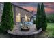 Brick house backyard featuring a fire pit with Adirondack chairs, tall privacy trees, and an outdoor dining area at 1116 Crooked River Dr, Waxhaw, NC 28173