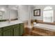 Bright bathroom featuring a soaking tub, walk-in shower and an olive colored vanity at 1116 Crooked River Dr, Waxhaw, NC 28173