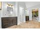 Bright bathroom featuring double sinks with dark wood cabinets and travertine flooring leading to the main bedroom at 1200 Churchill Downs Dr, Waxhaw, NC 28173
