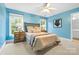 Bedroom featuring neutral carpet, two bright windows with wooded views, a ceiling fan, and bedside tables at 1200 Churchill Downs Dr, Waxhaw, NC 28173