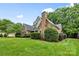 A side view of a brick house with a well-maintained lawn and manicured hedges at 1200 Churchill Downs Dr, Waxhaw, NC 28173