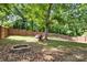 Fenced backyard featuring a fire pit and a dog house nestled under a mature shade tree at 137 Deal Ln, Statesville, NC 28677