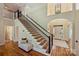 Grand staircase with dark metal railings, hardwood treads, and a view of the front door and foyer at 16430 New Providence Ln, Charlotte, NC 28277