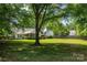 Expansive backyard with mature trees, lush lawn, fenced perimeter, and covered back porch at 1666 Sam Smith Rd, Fort Mill, SC 29708