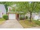 Inviting two-story home with a brick-accented garage, complemented by lush greenery and mature trees at 2530 Cochrane Dr, Charlotte, NC 28269
