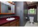 Bathroom with striped wallpaper, wood vanity, white sink, mirror, and toilet at 3012 Morgan Mill Rd, Monroe, NC 28110