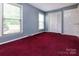 Well-lit bedroom featuring two windows and a closet, with red carpet, providing ample space and storage at 3012 Morgan Mill Rd, Monroe, NC 28110