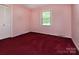 A lovely bedroom with pink walls, red carpet, closet, and a window providing natural light at 3012 Morgan Mill Rd, Monroe, NC 28110