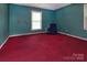 A serene bedroom featuring red carpet, a window, and soft blue walls, creating a cozy retreat at 3012 Morgan Mill Rd, Monroe, NC 28110