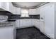Well-lit kitchen with white appliances, white cabinets, black hardware, and dark flooring at 3012 Morgan Mill Rd, Monroe, NC 28110