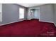 Spacious living room with large windows, fresh gray paint, and red carpeting at 3012 Morgan Mill Rd, Monroe, NC 28110