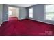 Open living room featuring red carpeting, fresh gray paint, and windows providing natural light at 3012 Morgan Mill Rd, Monroe, NC 28110
