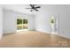 Bright, empty primary bedroom featuring a ceiling fan and sliding glass doors leading to the backyard at 5209 Carden Dr, Charlotte, NC 28227