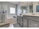 Well-lit bathroom boasting a double vanity, large mirror, and separate bathtub, offering a spa-like experience at 6001 Pine Cone Ln, Monroe, NC 28110