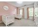 This bedroom has two cribs, light pink accent wall, light carpet, and good natural light at 618 Chase Ct, Fort Mill, SC 29708