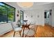 Bright dining room features a modern lighting fixture, a round glass table, and a view of the landscaped yard at 6508 Trenton Pl, Charlotte, NC 28226