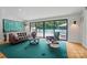 A modern living room features a green rug, large windows, and views of the luxurious swimming pool and backyard at 6508 Trenton Pl, Charlotte, NC 28226