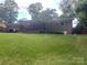 Expansive backyard with lush green grass, mature trees, and a covered porch perfect for outdoor enjoyment at 734 Harris Nw St, Concord, NC 28025