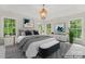 Bright main bedroom with a large bed, bench, and windows overlooking lush greenery at 121 Northampton Dr, Mooresville, NC 28117