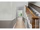 Inviting home hallway with wainscoting, leading to a staircase with a wood banister at 16565 Kimbolten Dr, Huntersville, NC 28078