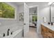 Bright bathroom featuring a soaking tub under a window and an open doorway to the bedroom at 2108 Lakeview Cir, Matthews, NC 28105