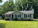 Charming one-story home with gray siding, black shutters, and a well-manicured lawn and mature trees at 5008 Delivau Dr, Charlotte, NC 28215